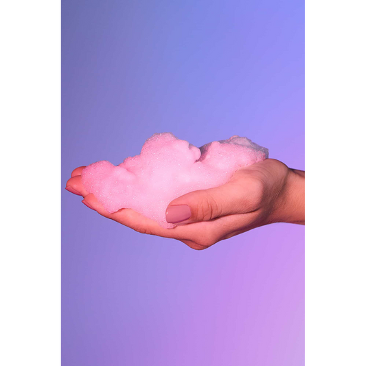 Mousse rose aérienne tenue dans la main sur fond violet pastel - Oh My God'Z