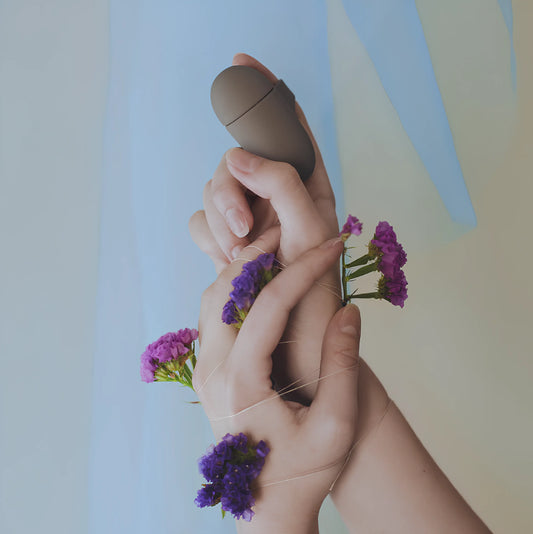 Le sextoy de luxe Better Than Your Ex par Bijoux Indiscrets, disponible chez Oh My God'Z. Ce vibromasseur discret, au design élégant et raffiné, est montré entre les mains entourées de fleurs, symbolisant la sensualité naturelle et le plaisir raffiné.