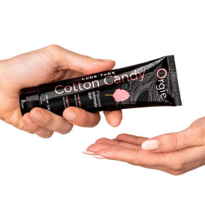 Une personne tenant un tube de lubrifiant Lube Tube Cotton Candy (Barbe à papa), avec une texture gel appliquée sur la main, illustrant son usage.