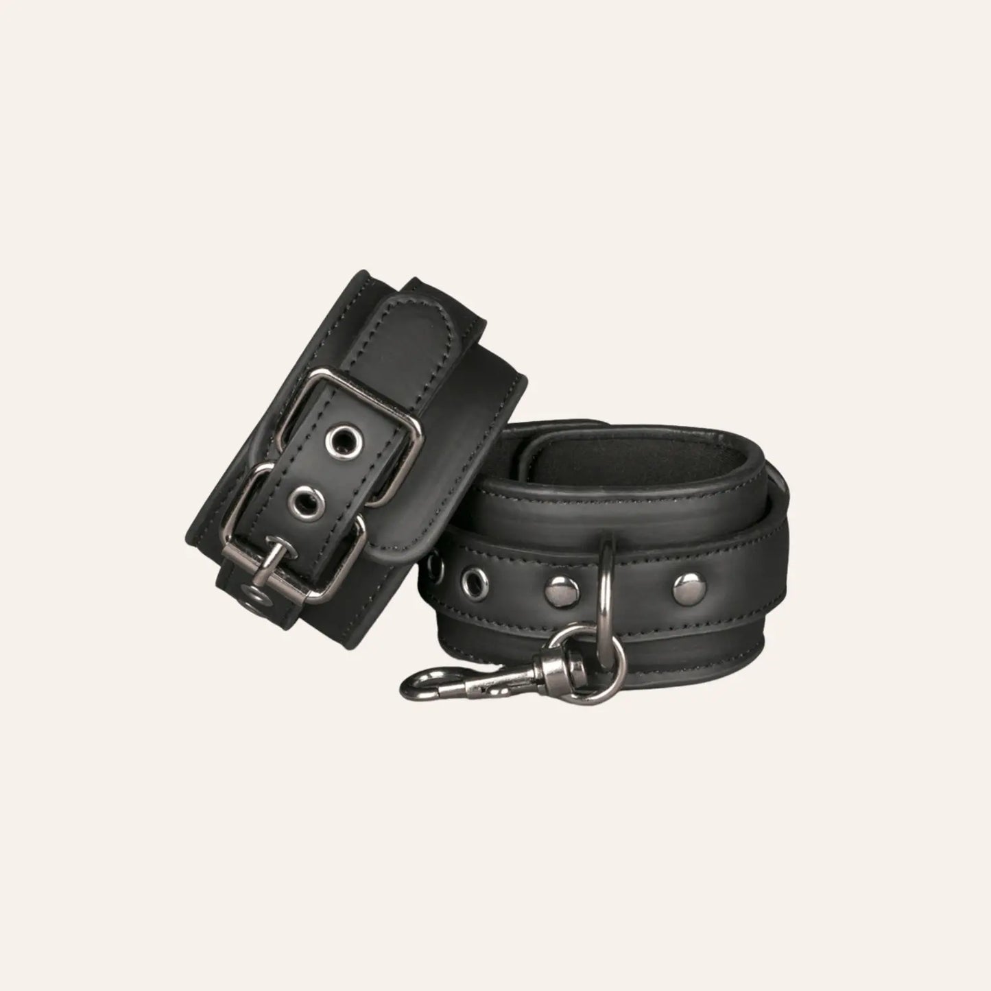 Zoom sur les menottes pour poignets Easytoys, conçues en cuir végan noir et dotées d'une attache centrale en métal. Un incontournable du bondage chic à retrouver chez Oh My God'Z, spécialisé dans les sextoys BDSM haut de gamme.
