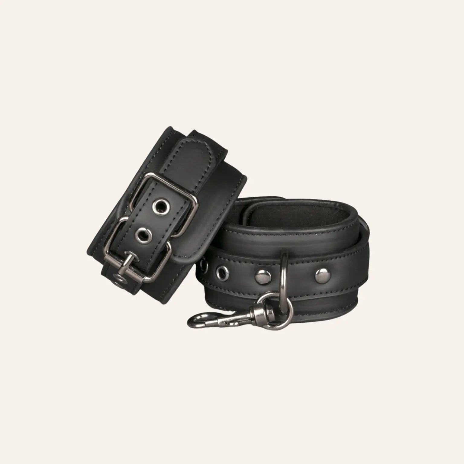Zoom sur les menottes pour poignets Easytoys, conçues en cuir végan noir et dotées d'une attache centrale en métal. Un incontournable du bondage chic à retrouver chez Oh My God'Z, spécialisé dans les sextoys BDSM haut de gamme.