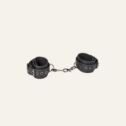 Vue détaillée des menottes en cuir synthétique noir avec fermetures métalliques robustes Easytoys Fetish Collection, proposées par la boutique Oh My God'Z. Idéales pour les expériences BDSM sophistiquées, ces menottes haut de gamme combinent sécurité et plaisir.