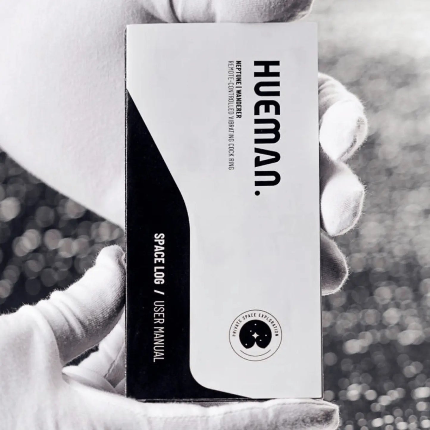 Manuel d’utilisation "Space Log" du sextoy Supernova Hueman, tenu par une main gantée blanche. Le livret souligne le positionnement premium et futuriste de la marque Hueman, distribuée par Oh My God'Z.
