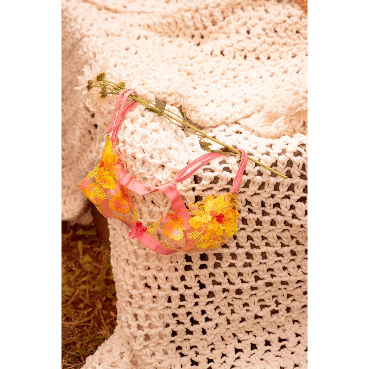 Ensemble lingerie rose et jaune Mapalé posé sur textile crocheté beige avec marguerites blanches - Oh My God'Z