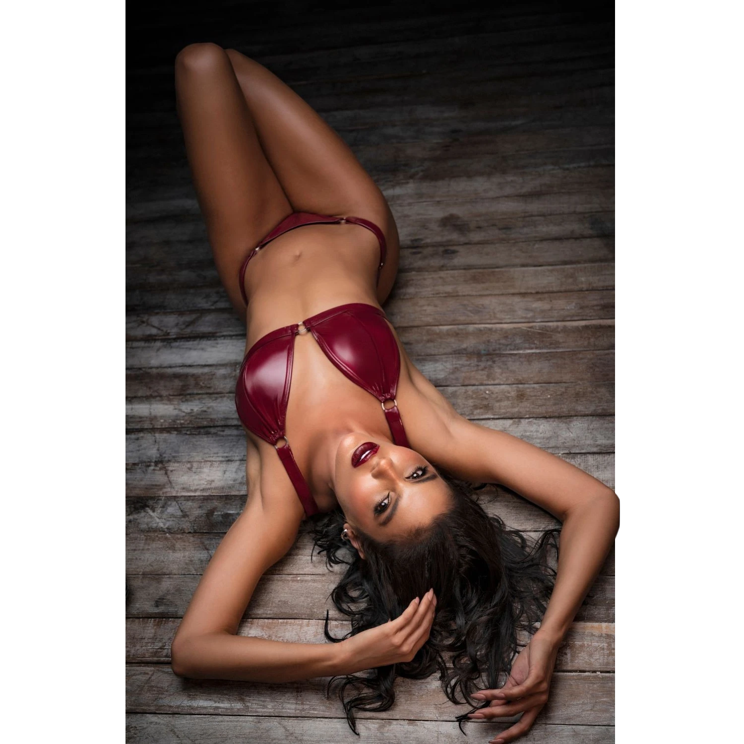 Femme allongée portant ensemble vinyle bordeaux deux pièces avec détails anneaux dorés - Oh My God'Z
