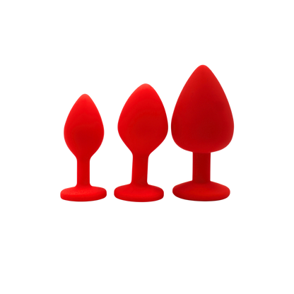 Trois plugs anaux bijou rouges en silicone medical presentes cote a cote par taille croissante - Oh My God'Z