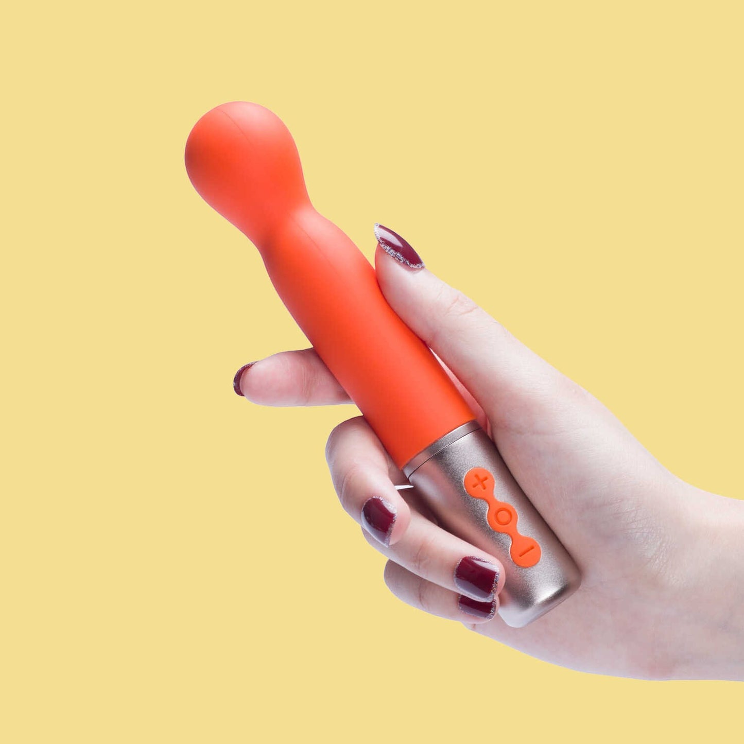 Vibromasseur orange à tête ronde tenu en main sur fond jaune, boutons de contrôle argentés - Oh My God'Z
